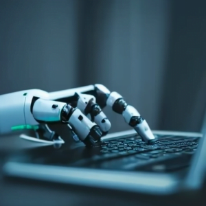 Robot hand typing on laptop